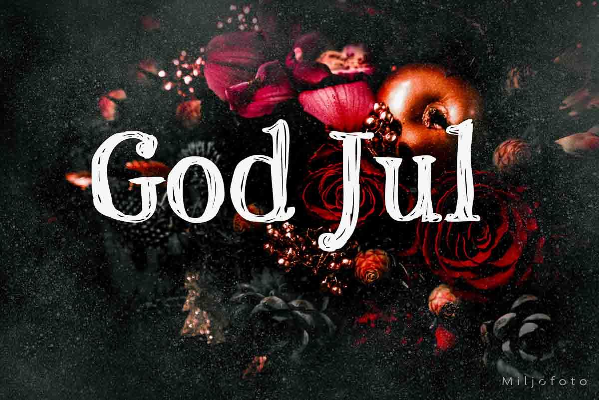 God jul med mørk bakgrunn Et julebilde med teksten "God Jul" skrevet i hvit, dekorativ skrift. Bakgrunnen er mørk og inneholder røde roser, kongler, glitter og gyldne epler, som skaper en varm og festlig julestemning.