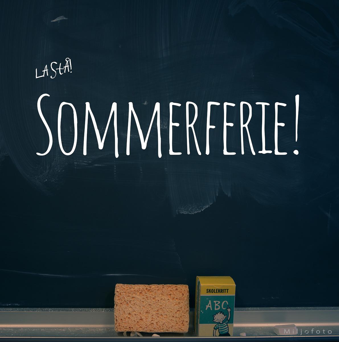 Sommerferie Sommerferie skrevet på en skoletavle, nedenfor ligger en svamp og en pakke med skolekritt.
