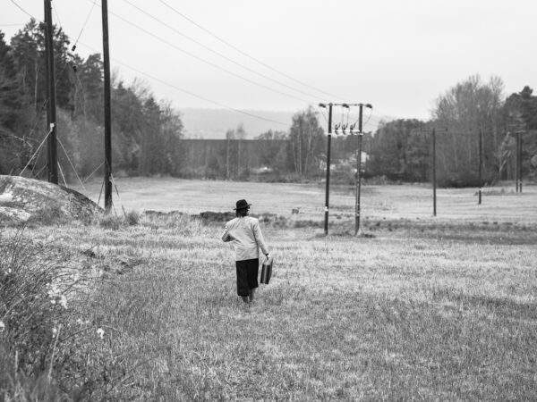 Mann i åker med stresskofert, på vei ut i livet, symboliserer at en grunder er på vei ut i markedet