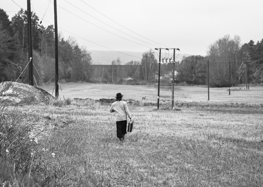 Mann i åker med stresskofert, på vei ut i livet, symboliserer at en grunder er på vei ut i markedet