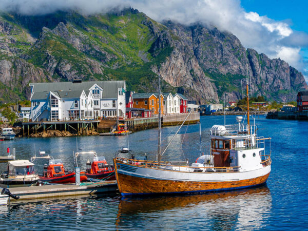 Foto av en Fiskebåt i Lofoten, som ligger til kai med fjell i bakgrunn