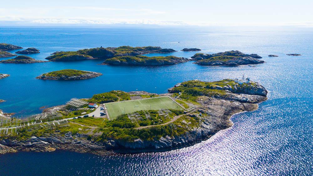 Bildet viser den verdenskjente fotballbanen i Henningsvær i Lofoten, som ligger spektakulært til på en liten, steinete øy omgitt av klart, blått hav.
