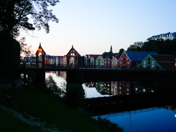 Bildet viser den ikoniske Gamle Bybro i Trondheim som strekker seg over Nidelva i det milde kveldslyset.