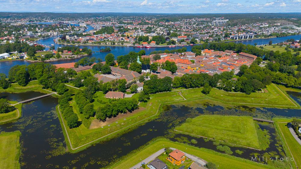 Bildet viser et vakkert luftfoto av Gamlebyen i Fredrikstad på en solrik sommerdag, preget av de karakteristiske stjerneformede vollgravene